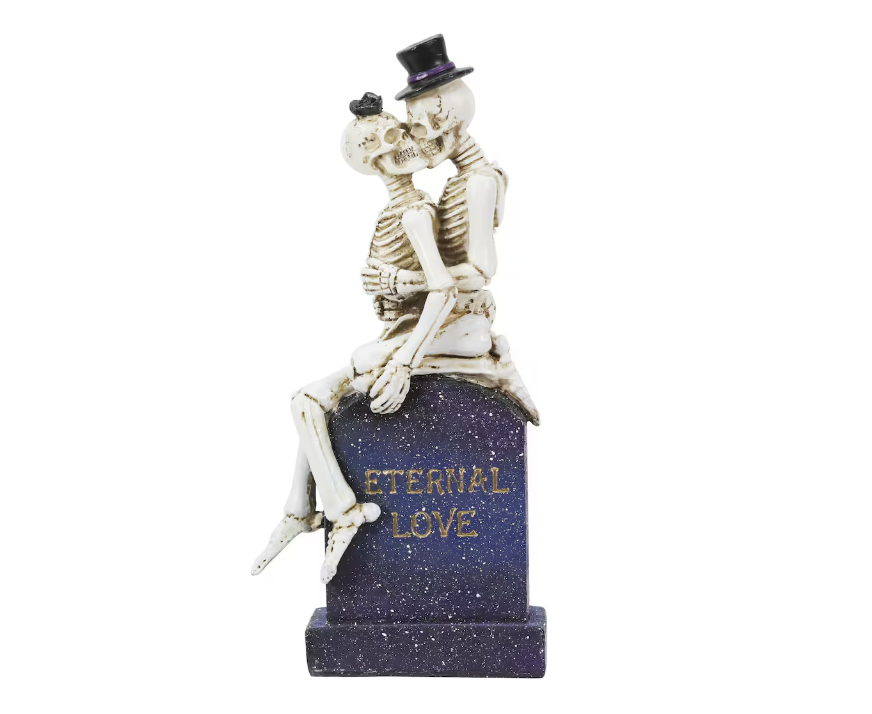 skeleton figurine featuring two skeletons kissing on a tombstone